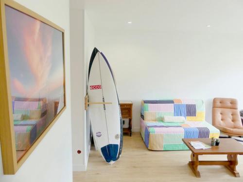 une planche de surf penchée contre un mur dans un salon dans l'établissement Appartement Tout Confort-Plage & Centre à Pied, à Seignosse