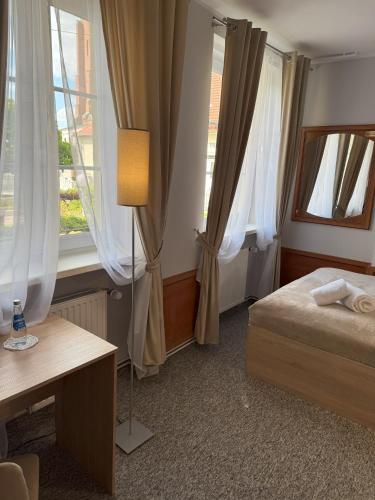 a bedroom with a bed and a desk and windows at Adalbertus Dom Pielgrzyma in Gniezno