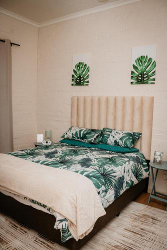 a bedroom with a bed and two plants on the wall at Mooi Uitsig Lodge in Paarl