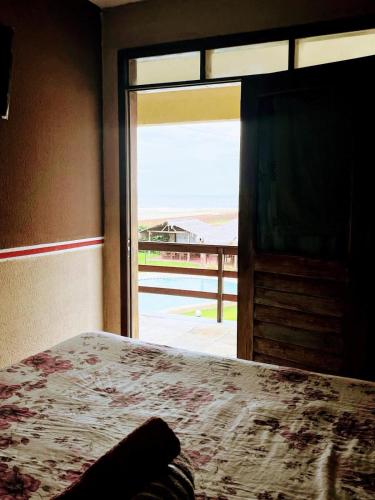 a bedroom with a bed and a window with a view at Ondas do mar Taiba Residence in Taíba