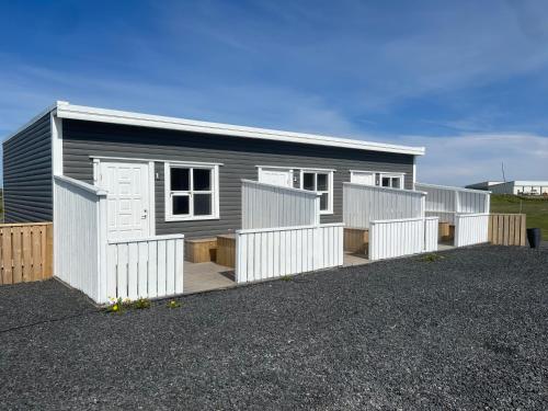 a small grey house with a white fence at Garður Apartments in Gardur