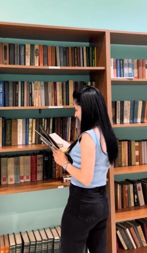 a woman reading a book in a library at Ani Resort in Artavaz