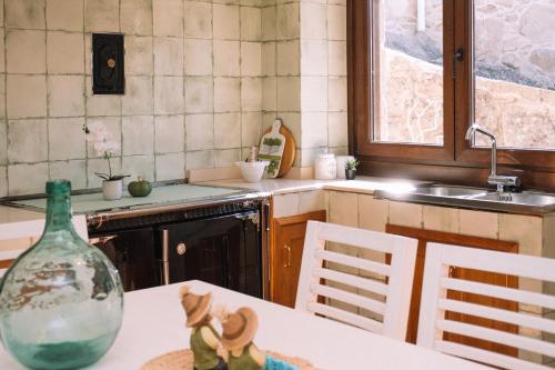 una cucina con un tavolo con una bottiglia di vetro sopra di O Lar do Bispo by CABANA Rentals a Arbo