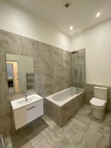 a bathroom with a tub and a toilet and a sink at Stunning 1 Bed Apartment - Perfect for Couples or Solo Stays in Tadworth