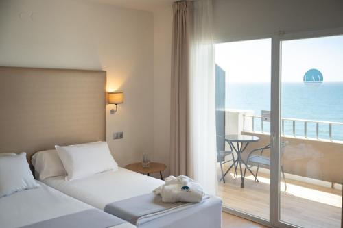 a hotel room with a bed and a balcony with the ocean at FAY Victoria Beach in Rincón de la Victoria