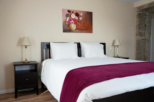 a bedroom with a large white bed and a painting at A Casa de Sobrado - Countryside House in Barros