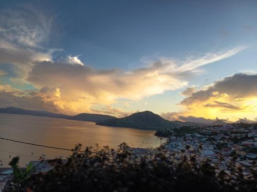 a sunset over a city and a body of water at Appartement Belsol Ambiance tropicale et détente in Sada