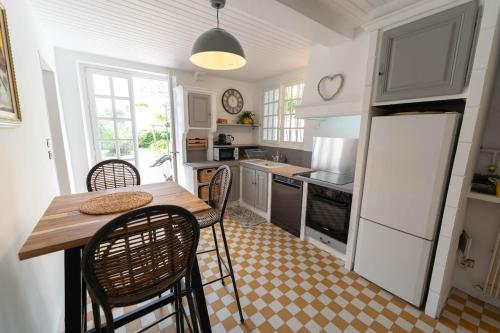 une cuisine avec une table, des chaises et un réfrigérateur dans l'établissement Jolie maison avec jardin, à 500m de la plage, à Cagnes-sur-Mer
