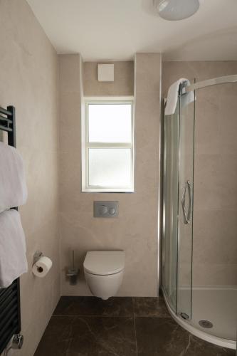 a bathroom with a toilet and a window and a shower at The Salthouse Hotel in Ballycastle