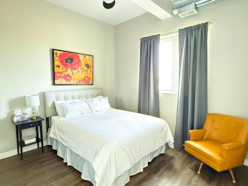 a bedroom with a bed and a chair and a window at Contemporary East Loft in Historic Niagara in Niagara on the Lake