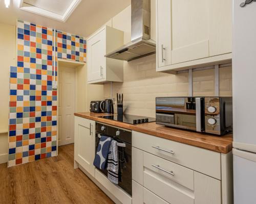 a kitchen with white cabinets and a microwave at Harbour place in Newcastle under Lyme with Parking, perfect for Contractors or Alton Towers in Stoke on Trent