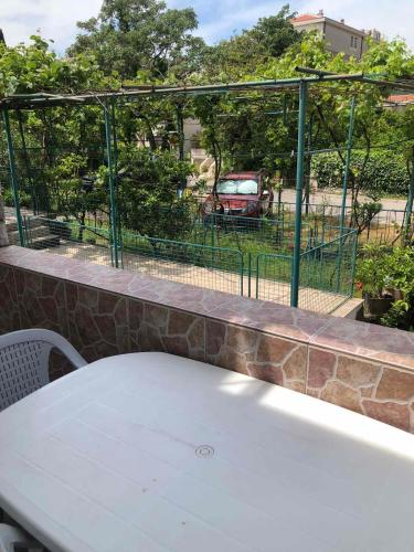 a table and a fence with a car in a parking lot at Apartmani Centar in Petrovac na Moru