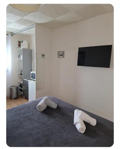 - une chambre avec 2 serviettes sur un lit et une télévision à écran plat dans l'établissement Chambres au 1er étage d'une villa, à Ponteilla