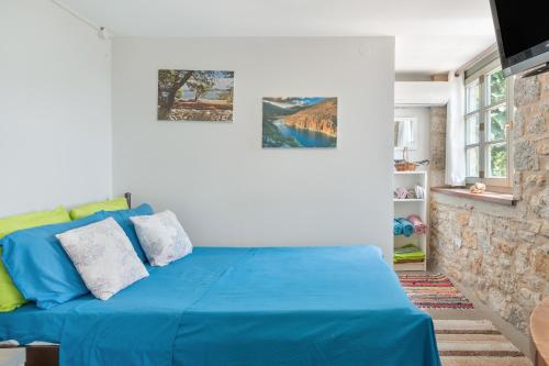 een slaapkamer met een blauw bed en 2 schilderijen aan de muur bij Boutique Stone Cottage House in Panormos Kalymnos