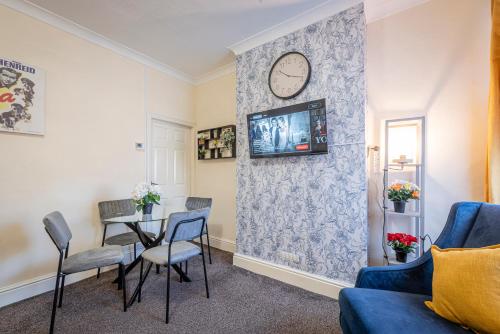 a living room with a table and a clock on a wall at Harbour place in Newcastle under Lyme with Parking, perfect for Contractors or Alton Towers in Stoke on Trent