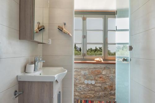 een badkamer met een wastafel en een raam bij Boutique Stone Cottage House in Panormos Kalymnos