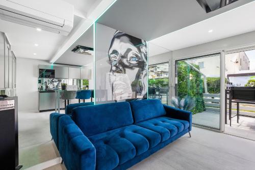 - un canapé bleu dans un salon avec une cuisine dans l'établissement Village Naturiste R4N - La Villa Double Game Luxe, au Cap d'Agde