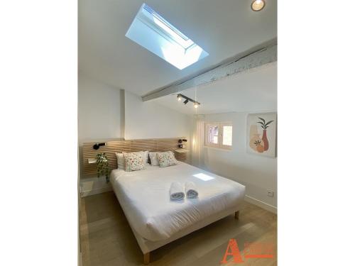 - une chambre avec un lit doté de draps blancs et une lucarne dans l'établissement Appartement avec Terrasse privée sur les toits de Toulouse, à Toulouse