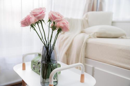 a vase with pink roses on a table next to a bed at 鎌倉四丁目 in Tokyo