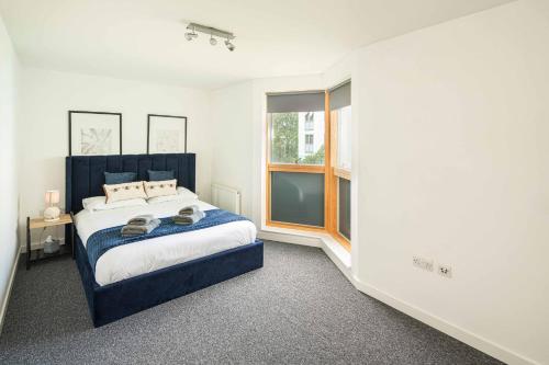 a bedroom with a blue bed and a window at Homey and Secure apartment - Wembley Stadium! in London