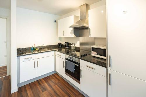 a kitchen with white cabinets and stainless steel appliances at Homey and Secure apartment - Wembley Stadium! in London