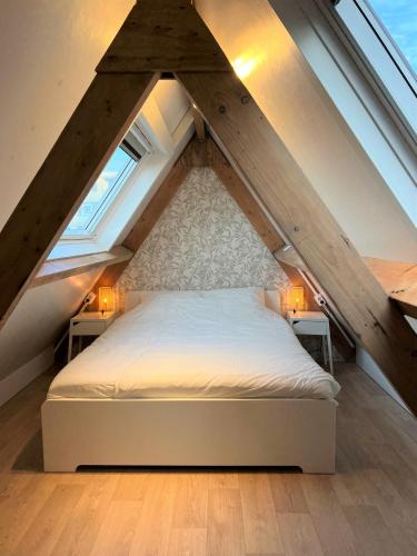 a bedroom with a white bed in the attic at Moana3 Seaview in Egmond aan Zee
