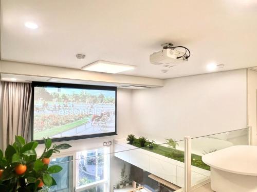 een woonkamer met een groot projectiescherm op de muur bij Hongdae Luxury Stay in Seoul