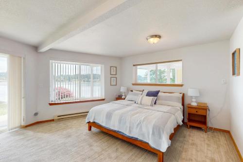 a bedroom with a large bed and two windows at Waterfront Retreat at Church Point in Shelton