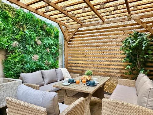 un patio avec une pergola en bois et une table et des chaises dans l'établissement Le loft du Cloître - Parking - Clim, à Avignon