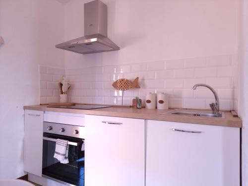 a kitchen with white cabinets and a sink and a stove at Residenza C 1-13 Porto Ottiolu in Porto Ottiolu