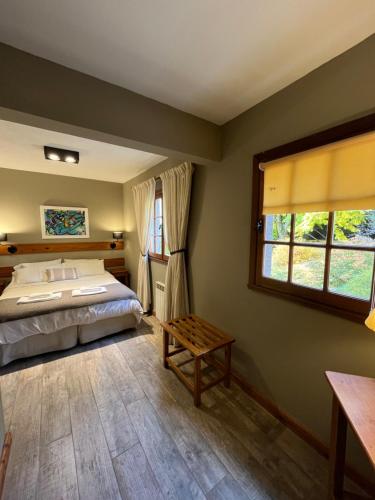 um quarto com uma cama, uma janela e uma mesa em Las Marianas Hotel em San Carlos de Bariloche