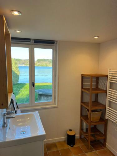 une salle de bain avec un lavabo et une grande fenêtre dans l'établissement Les cabanes du pêcheur, à Crach
