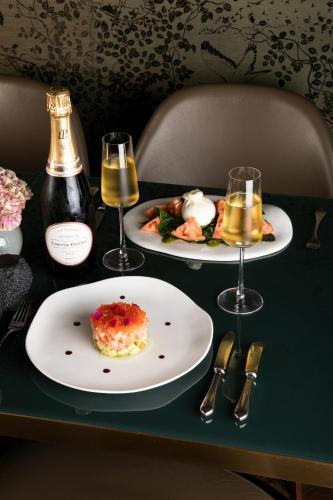 a table with two plates of food and two glasses of wine at Hotel Mercer Sevilla 5 GL in Seville