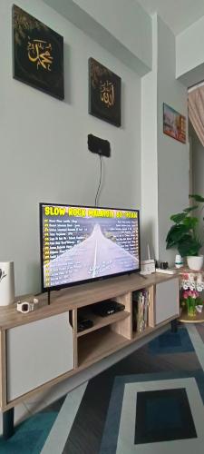 a flat screen tv on a wooden entertainment center in a living room at M.FR Homestay Pangsapuri Putra Damai in Putrajaya