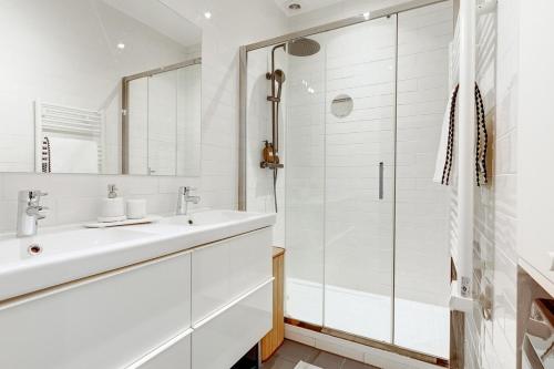 une salle de bain blanche avec un lavabo et une douche dans l'établissement Le Marais Chic by Ecoflats, à Paris