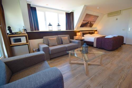 a hotel room with a bed and a couch and a table at Hotel Noordzee in Domburg