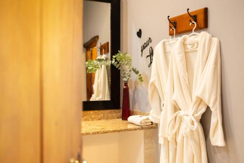 a bathroom with a mirror and a robe on a shelf at De Opstal Country Lodge in Oudtshoorn