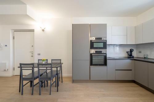 una cucina con mobili bianchi e un tavolo con sedie di Parco Comfort Suite Battaglia Appartamenti a Milano