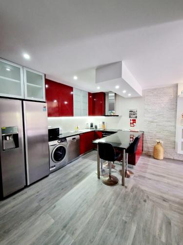 a kitchen with red cabinets and a table and a refrigerator at Apartamento Armanbel in Sesimbra