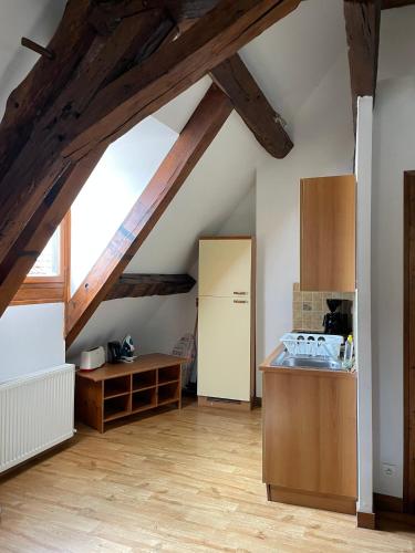 une cuisine mansardée avec poutres en bois et un réfrigérateur blanc dans l'établissement Domaine de Vandenesse Et Spa, à Vandenesse-en-Auxois