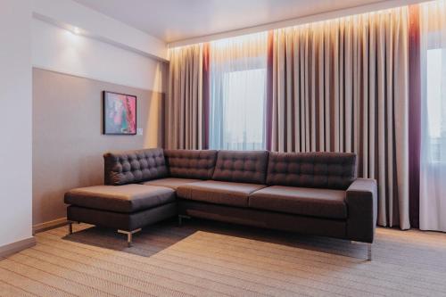 a living room with a brown couch and a chair at Premier Inn Köln City Mediapark in Cologne