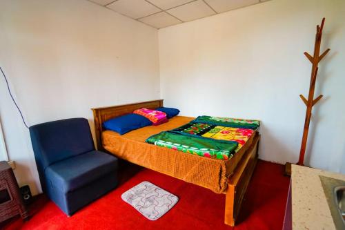 a small bedroom with a bed and a blue chair at Himalaya cabin in Nuwara Eliya