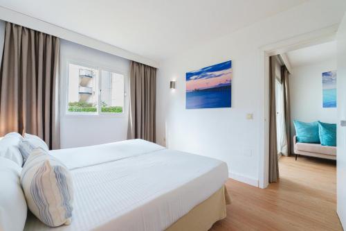 a white bedroom with a bed and a couch at Apartamentos Caprice Playa de Alcudia in Port d'Alcudia