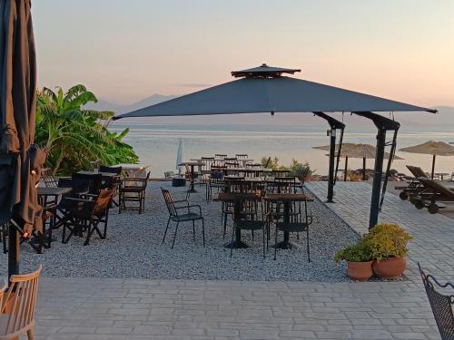 a group of tables and chairs with an umbrella on the beach at Skipper's Apartments in Akrata
