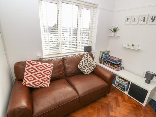 a brown leather couch in a living room with a window at Afallon in Menai Bridge