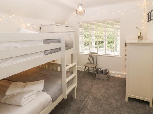 a bedroom with two bunk beds and a chair at Afallon in Menai Bridge