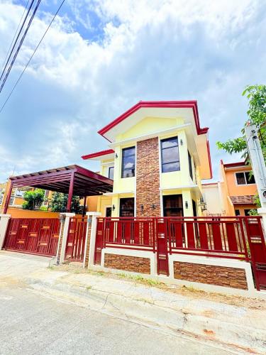a house with a red fence in front of it at Mi Casa Nova in Bacolod