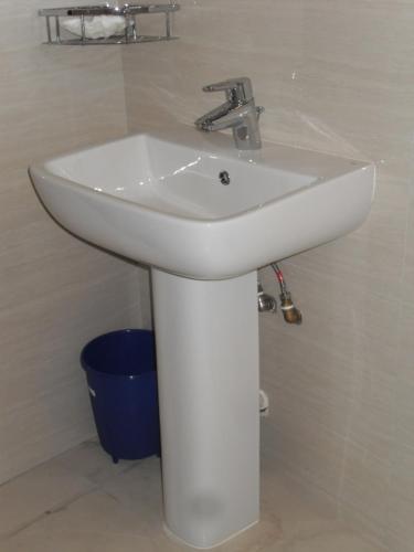 a white sink in a bathroom with a blue bucket at Bee Nest Bed & Breakfast in Negombo