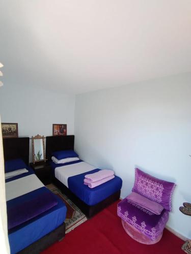 a room with two beds and a chair at story house salah in Rabat