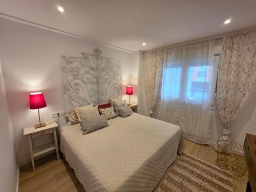 a bedroom with a bed with two lamps and a window at Avilés Luce B - 3 habitaciones - 2 baños - VUT-7461-AS in Avilés